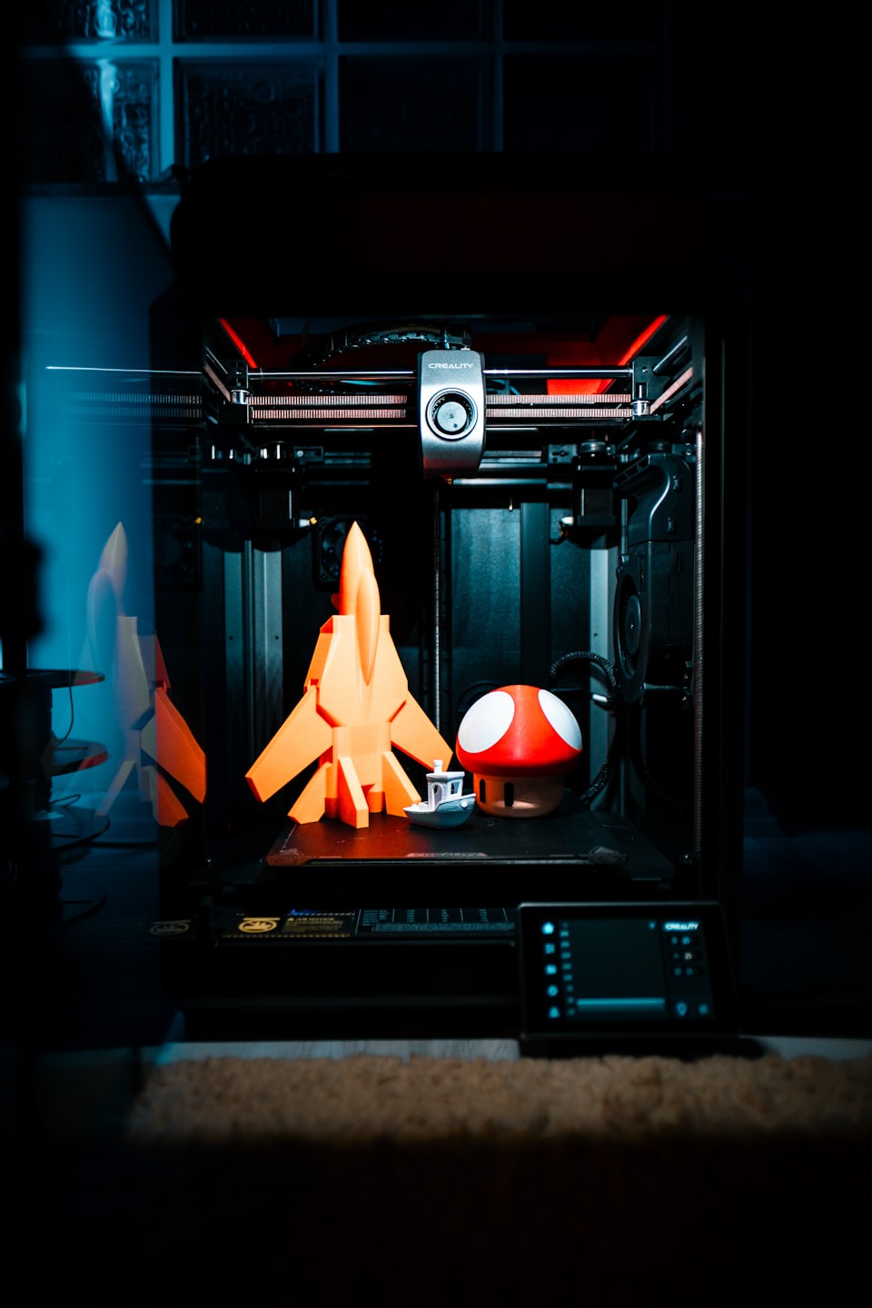 Impresora 3D imprimiendo figuras: un cohete, una nave y una seta